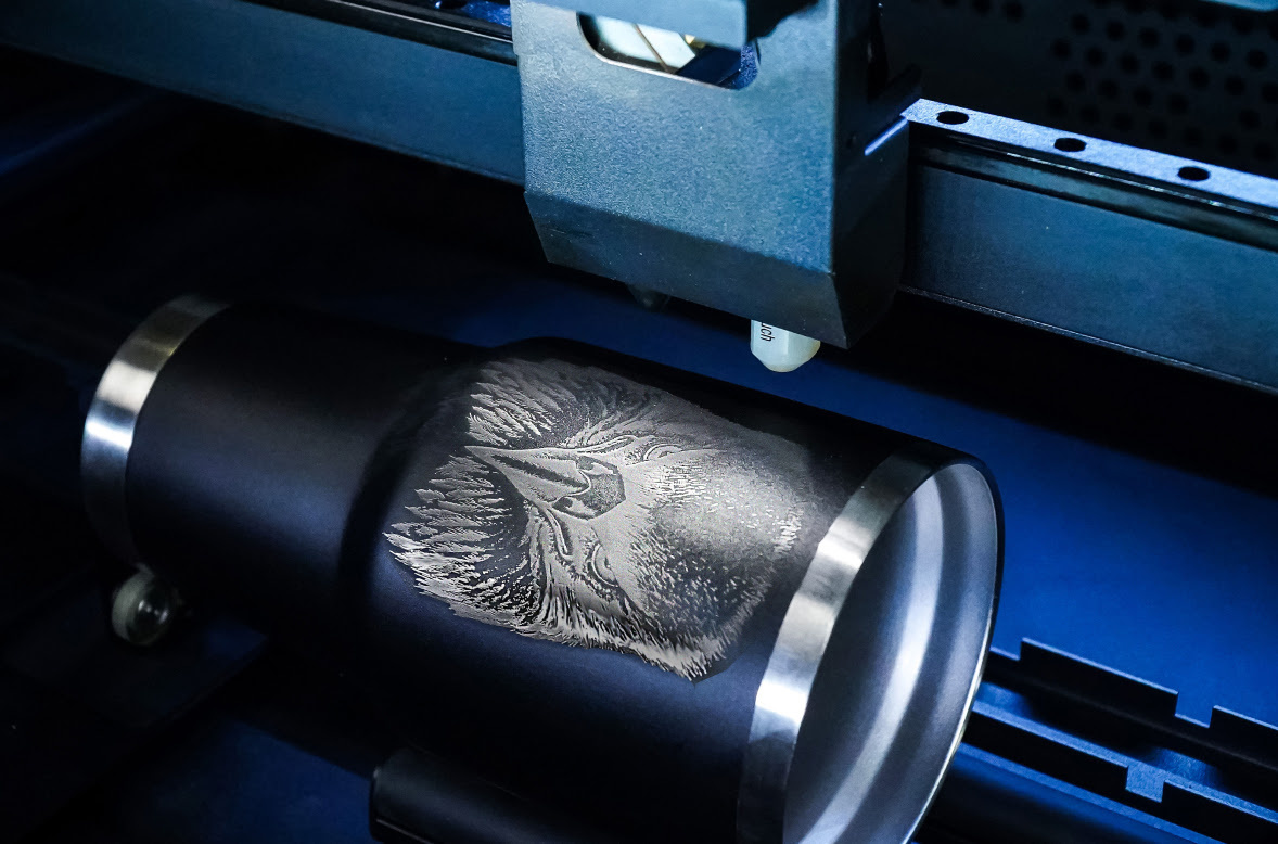 Metalna čaša u FLUX Beambox Pro, držana rotacionim modulom, gravirana motivom orla.